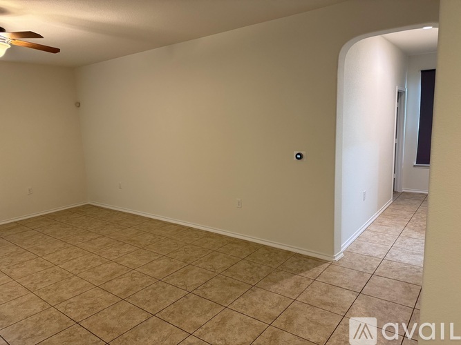 A room with beige tiled flooring and a ceiling fan.