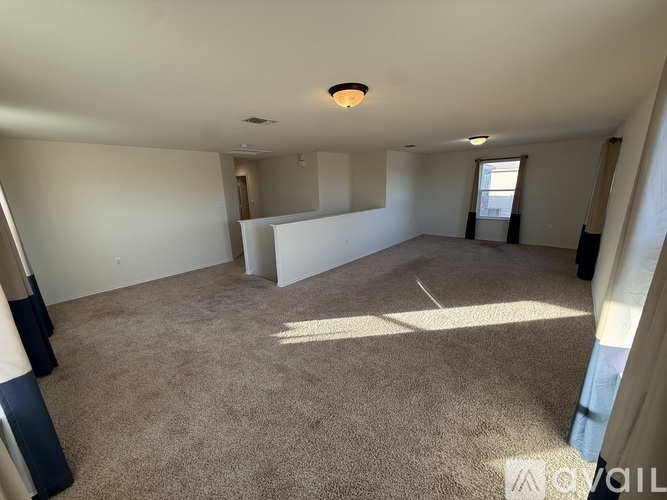 A spacious room with a carpeted floor and a window letting in natural light.