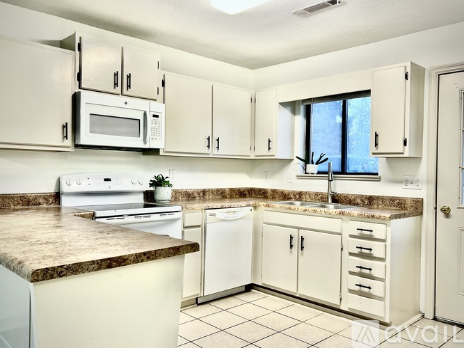 A kitchen with white cabinets and a marble countertop.