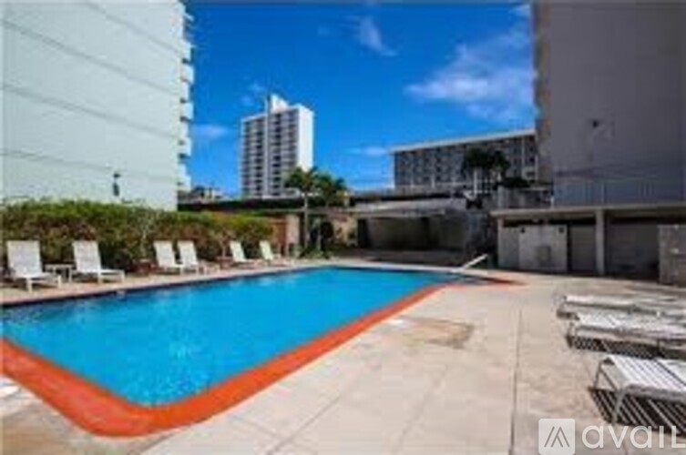 A pool with chairs around it and buildings in the background.