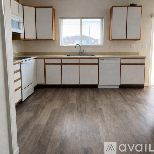 A kitchen with white cabinets and a wooden floor.