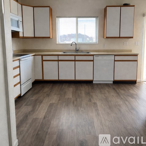 A kitchen with white cabinets and a wooden floor.