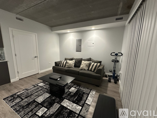 A modern living room with a grey couch and a black and white rug.