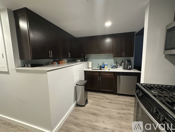 A kitchen with dark brown cabinets and a white countertop.