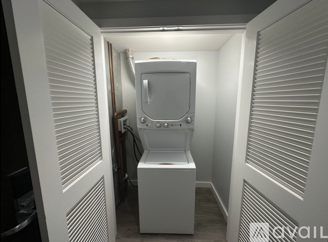 A small white washing machine is in a narrow space between two walls.