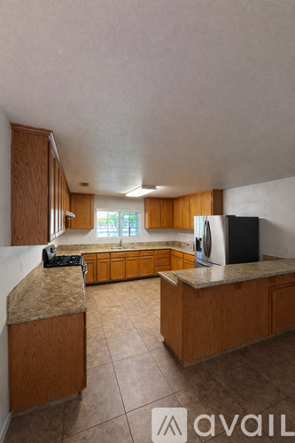 A kitchen with wooden cabinets and a black refrigerator.