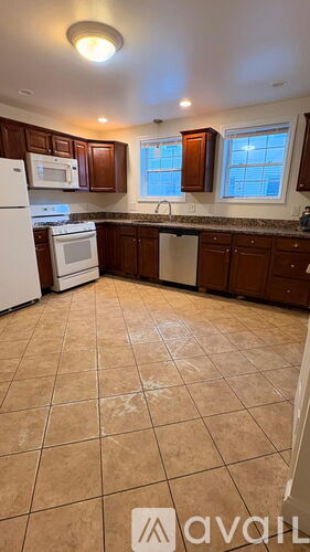 A kitchen with brown cabinets and a white refrigerator.