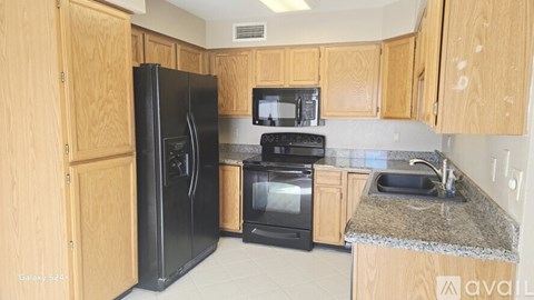 A kitchen with wooden cabinets and black appliances.