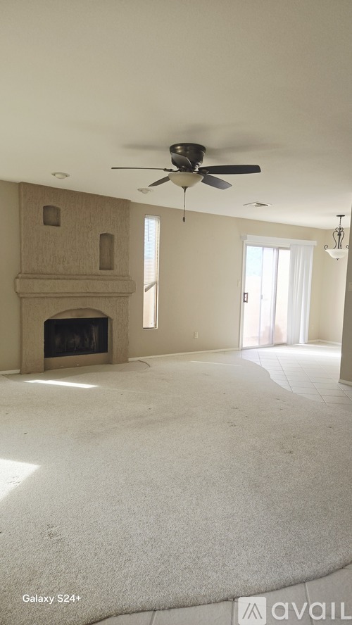 A living room with a fireplace and a ceiling fan.