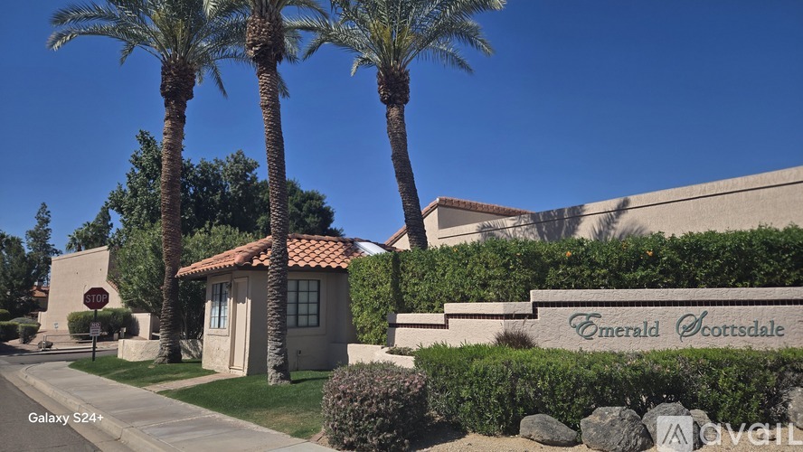 A building with palm trees in front and a sign that says Emerald Cottages.