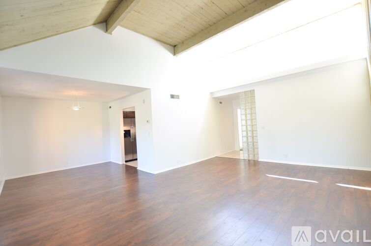 A spacious room with wooden floors and a white wall.