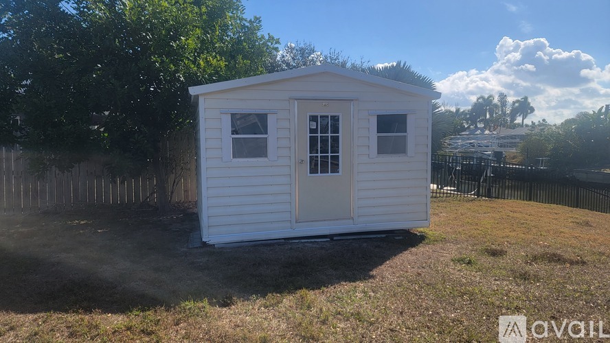 A small white house with a fence in the background.