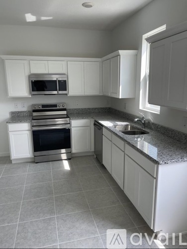 A kitchen with white cabinets and a granite countertop.