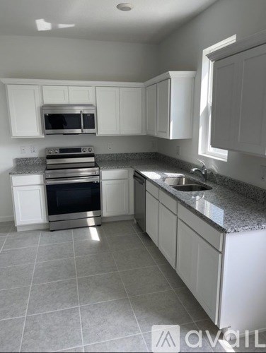 A kitchen with white cabinets and a granite countertop.