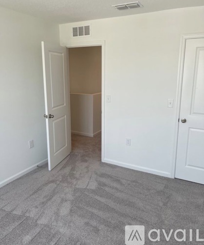 A room with a carpeted floor and a doorway leading to another room.