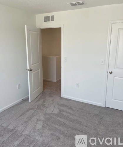 A room with a carpeted floor and a doorway leading to another room.