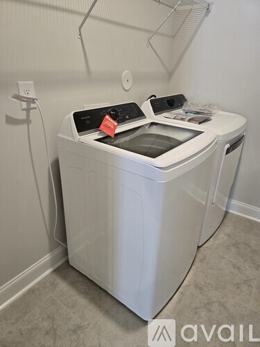A white washing machine with a black top and a red tag on it.