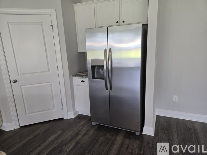 A kitchen with a stainless steel refrigerator and white cabinetry.