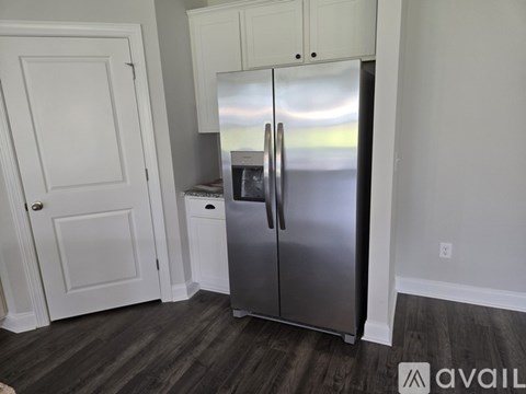 A kitchen with a stainless steel refrigerator and white cabinetry.