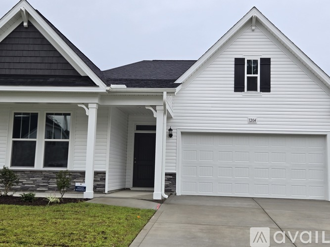 A white house with a black garage door and a window with black shutters.