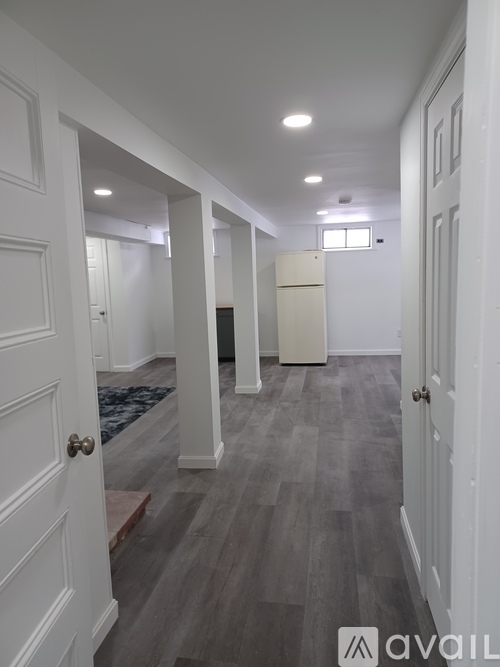A hallway with white doors and a grey floor.