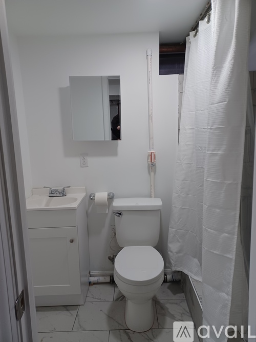 A white toilet sits in a bathroom next to a sink and a mirror.