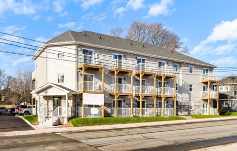 A two-story apartment building with balconies and a parking lot in front.