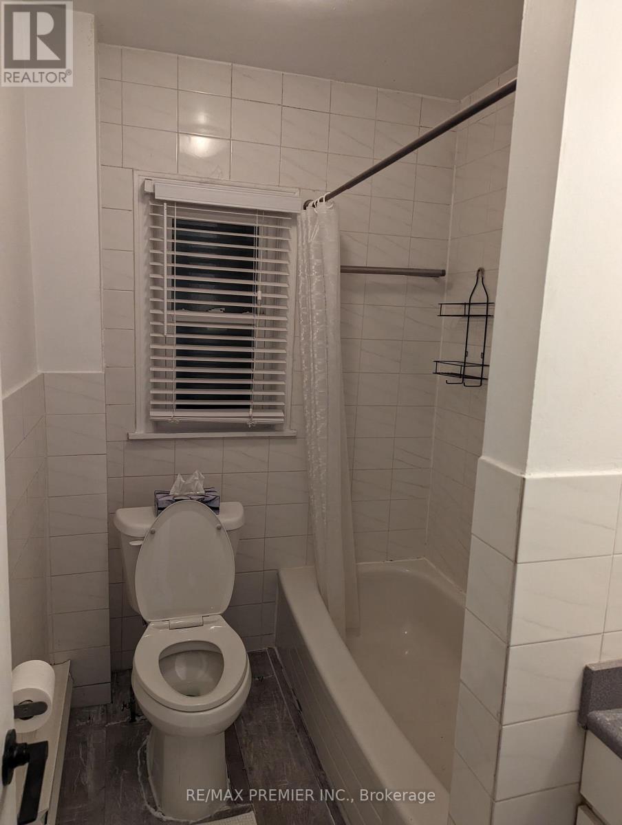 A white toilet in a bathroom with a white tiled wall.