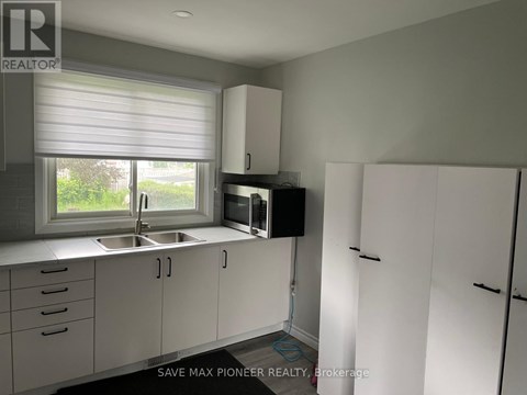 A kitchen with white cabinets and a window with blinds.