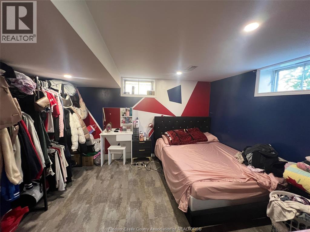 A bedroom with a bed, desk, and clothing rack.