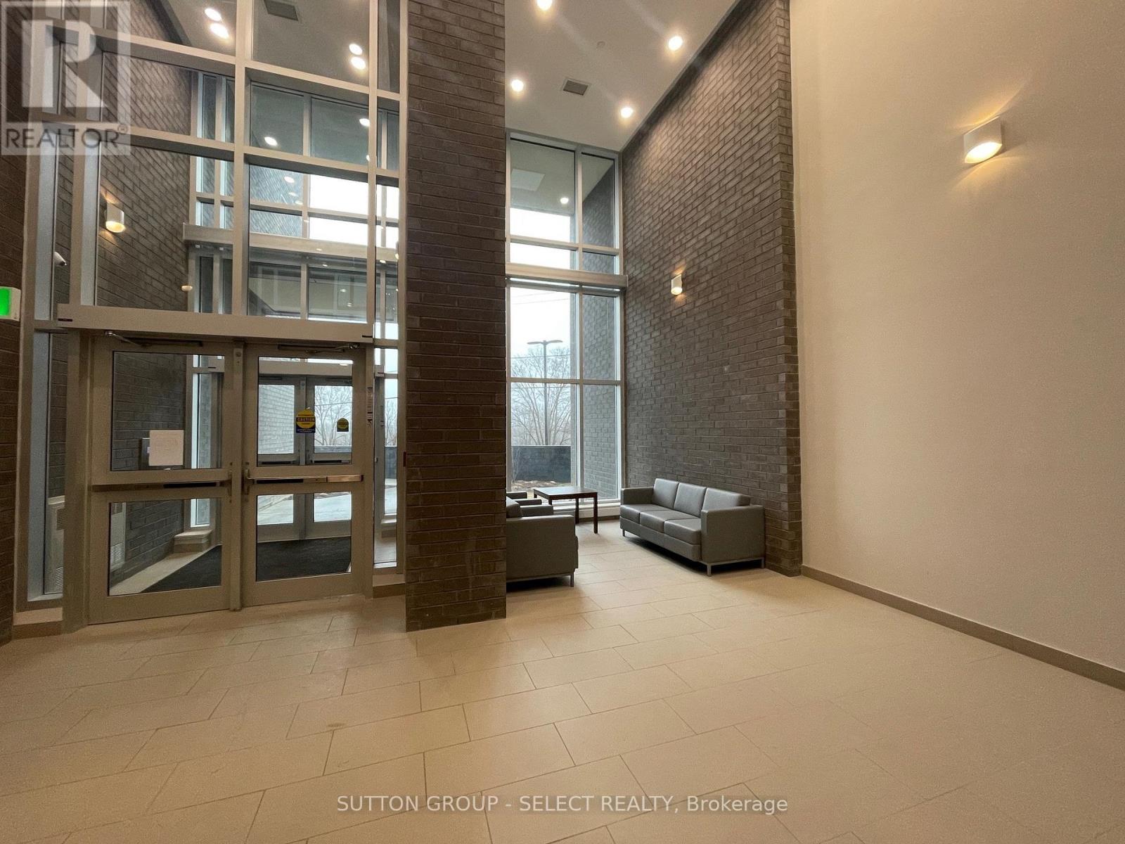 A hallway with a glass door and a brick pillar.