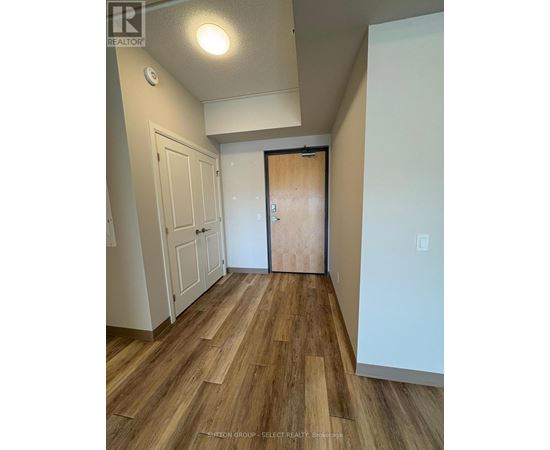 A hallway with wood flooring and a white door.