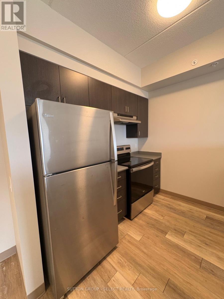 A stainless steel refrigerator in a kitchen with wooden flooring.