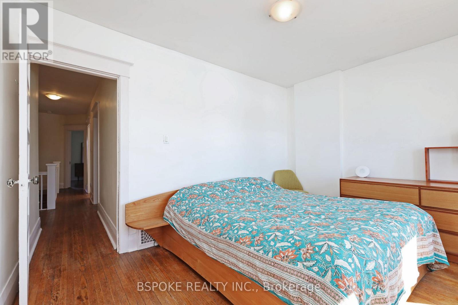 A bedroom with a bed, dresser and mirror.