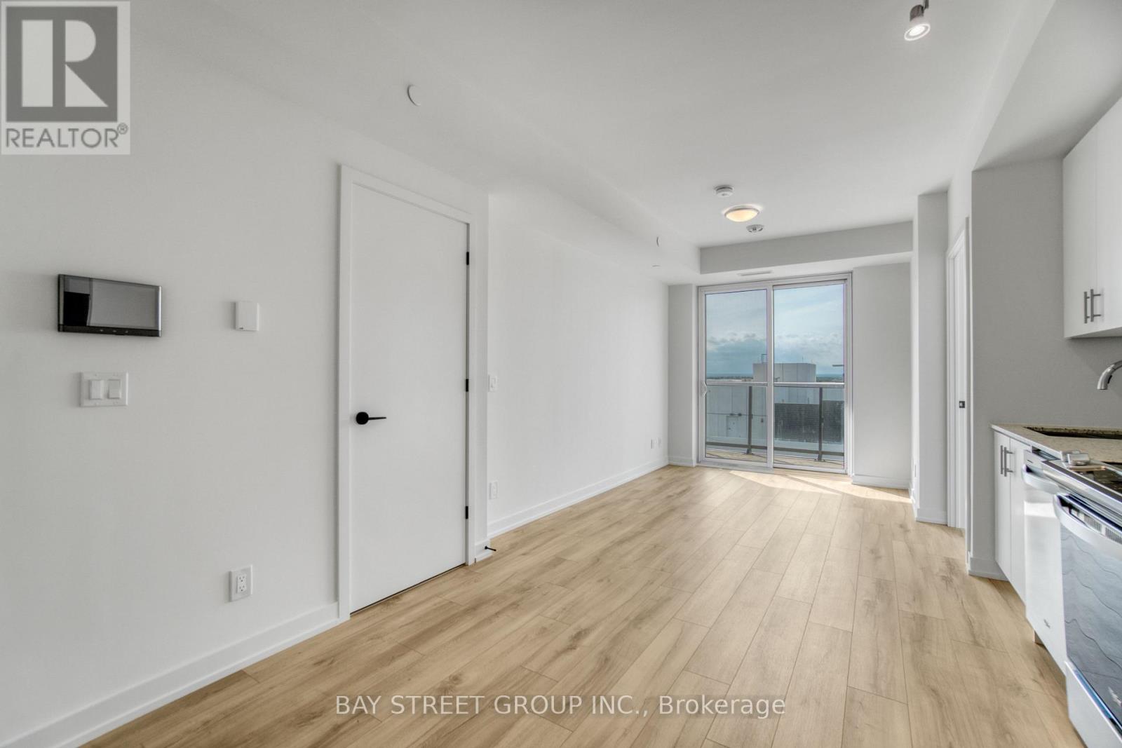 A spacious room with wooden flooring and white walls.