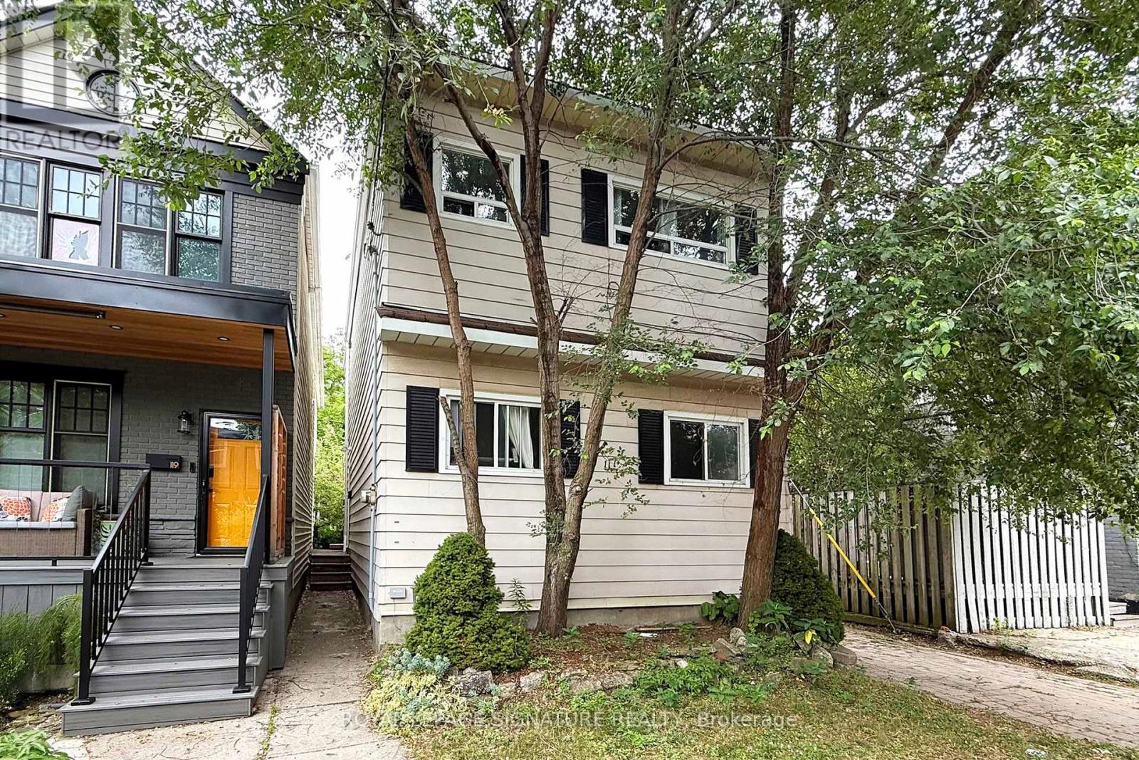 A house with a brown door is surrounded by trees.