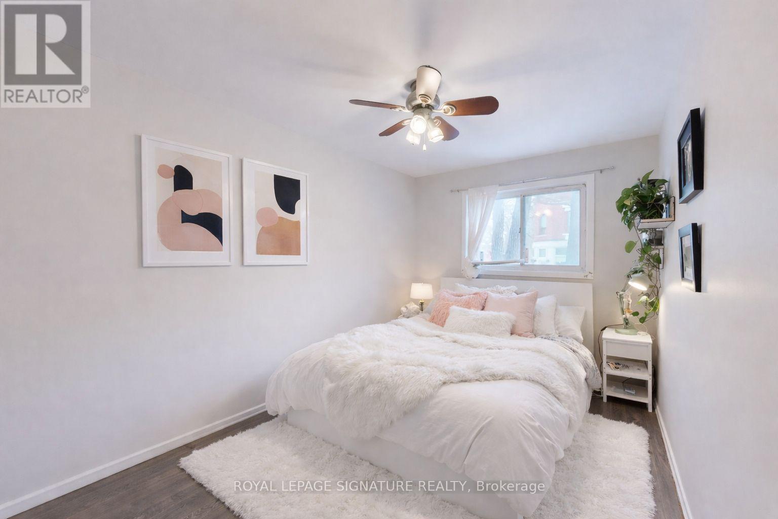 A bedroom with a white bed and a ceiling fan.