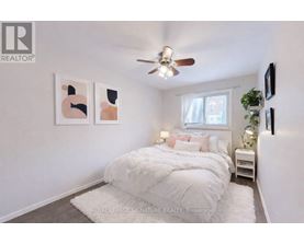 A bedroom with a white bed and a ceiling fan.