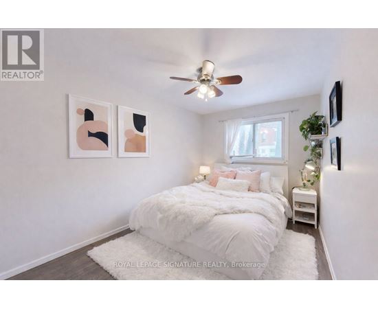 A bedroom with a white bed and a ceiling fan.