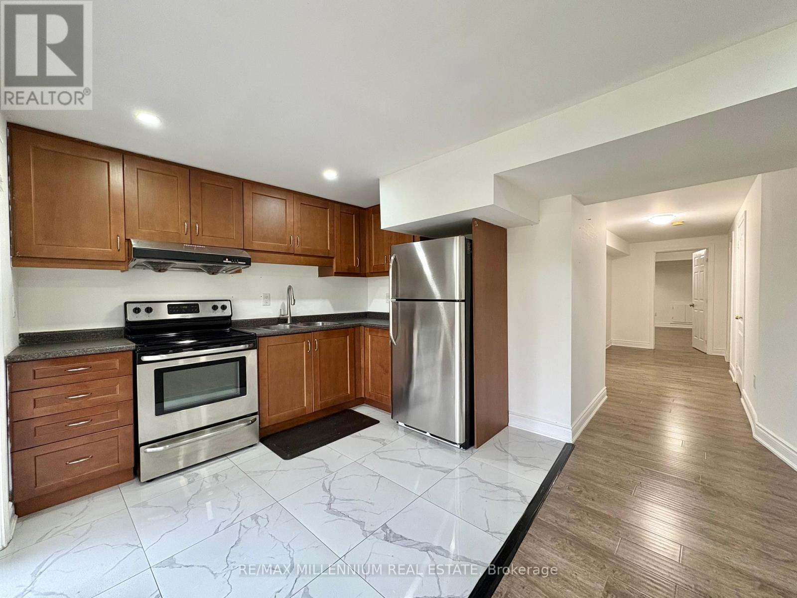 A kitchen with wooden cabinets and a marble floor.