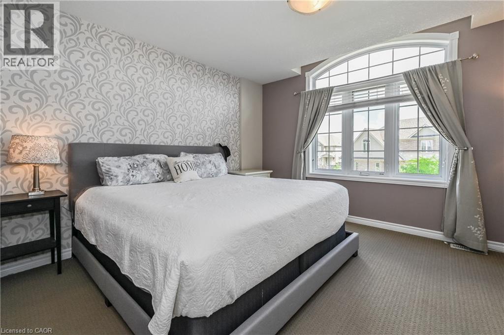 A bedroom with a large bed and a window overlooking a house.