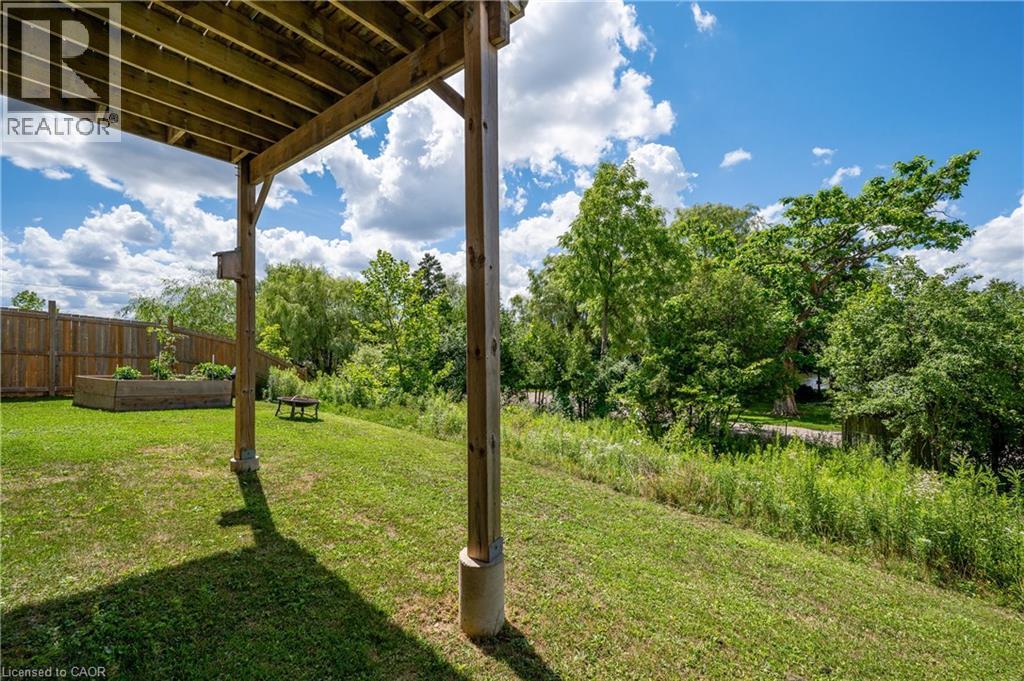 A wooden pergola overhangs a grassy area with a bench underneath.