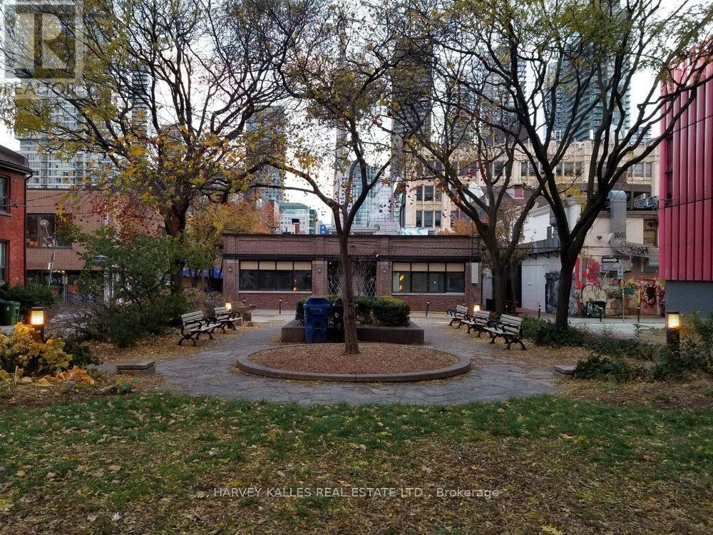 A park with a fountain surrounded by benches and trees.