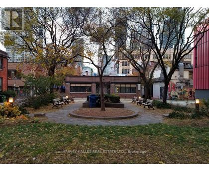 A park with a fountain surrounded by benches and trees.