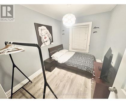 A bedroom with a bed, a dresser, and a painting of Marilyn Monroe.