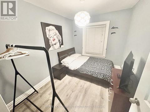 A bedroom with a bed, a dresser, and a painting of Marilyn Monroe.