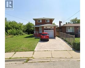 A red car is parked in front of a house with a realtor logo.