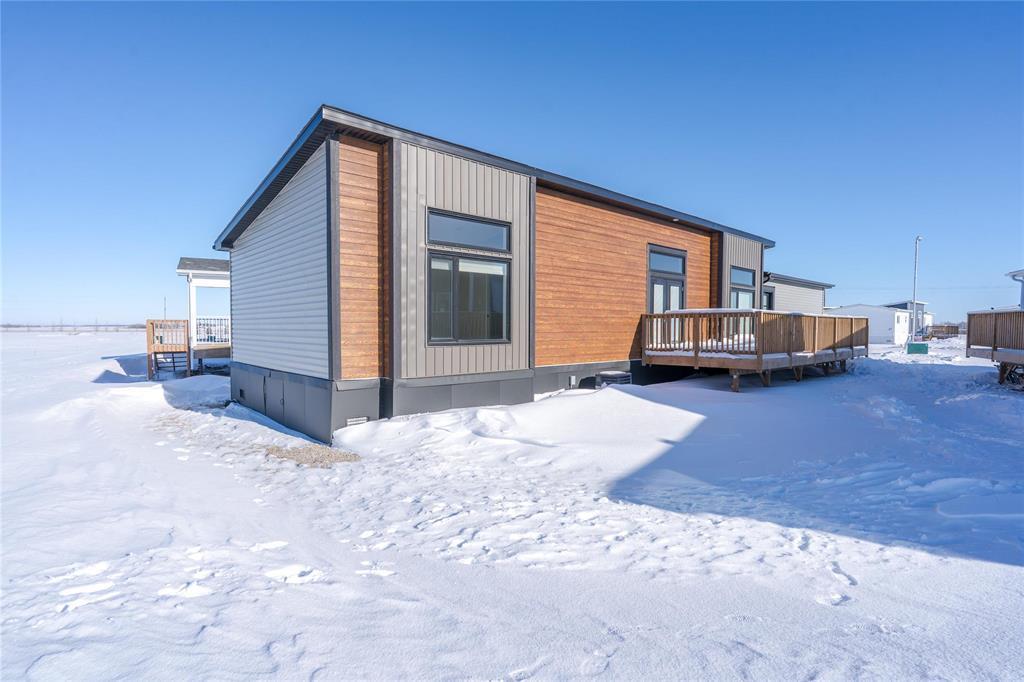 A house with a grey roof and a brown door is surrounded by snow.