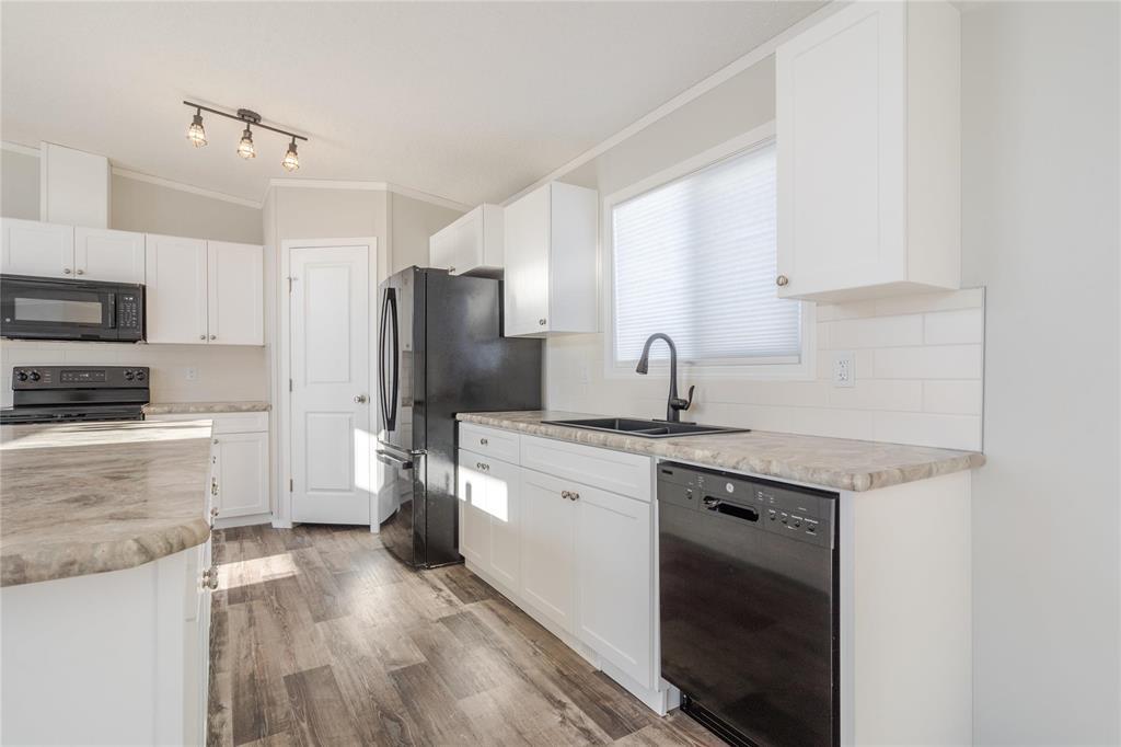 A kitchen with black appliances and white cabinets.