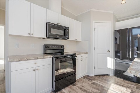 A kitchen with white cabinets and a black microwave above the stove.